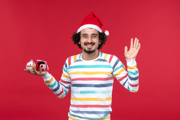 帽子正面图年轻人手持圣诞树玩具红墙新年人类节日红圣诞节玩具人