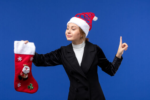 持有前景年轻女子手捧大圣诞袜在淡蓝色墙上过年过节年轻女性观点大