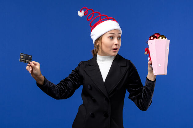 观点正面图年轻女士拿着银行卡在蓝墙钱过年情绪职业圣诞节