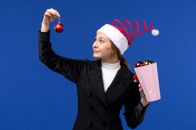 套装前视图年轻女性手持蓝色背景的圣诞树玩具蓝色的情绪新年假期情感肖像正面
