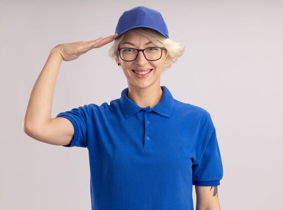 敬礼身穿蓝色制服 头戴帽子的年轻女送货员站在白色的墙上 面带微笑地致意女人帽子欢呼