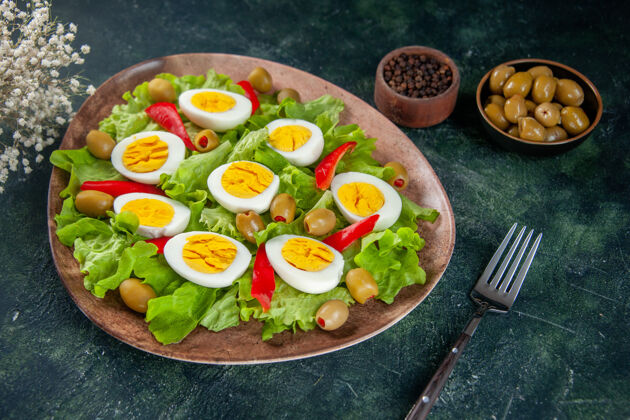 盘子正面图美味的鸡蛋沙拉由橄榄和绿色沙拉组成 背景为深色晚餐午餐鸡蛋沙拉