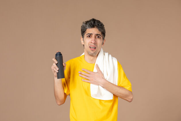 脸正面图：年轻男子拿着泡沫和毛巾准备在粉色背景上刮胡子准备粉色前面