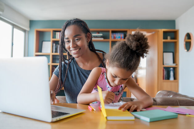 笔记本电脑母亲在家里帮助和支持女儿上网络学校新的正常生活方式理念单亲观念童年学生室内
