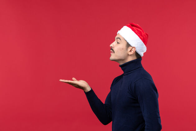 圣诞正面图红色背景上戴着红色节日帽的年轻男性帽子风景红色