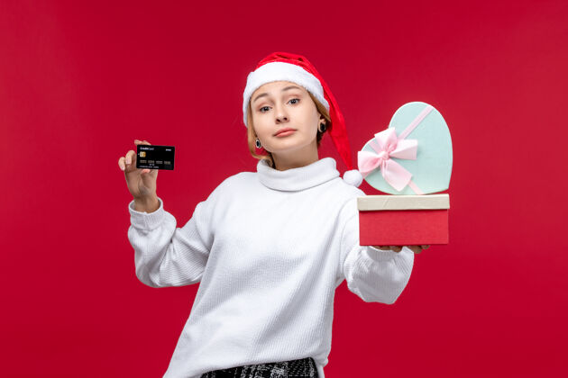 银行正面图：年轻女性 带着红色背景的银行卡和礼物卡片一肖像