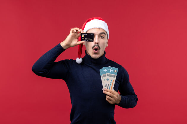 票正面图：年轻男性 带着红色背景的银行卡和票圣诞节红色肖像