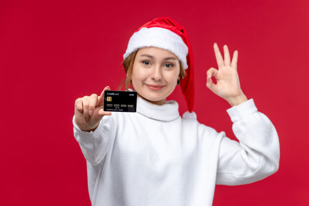 红色正面图红色背景上有银行卡的年轻女性圣诞节肖像微笑