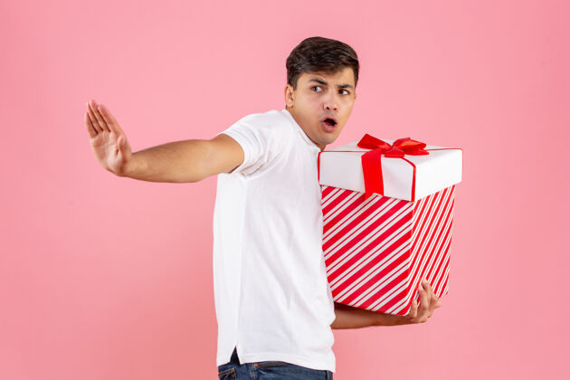 礼物正面是年轻男性 粉色背景上有一份圣诞礼物视图成人圣诞节