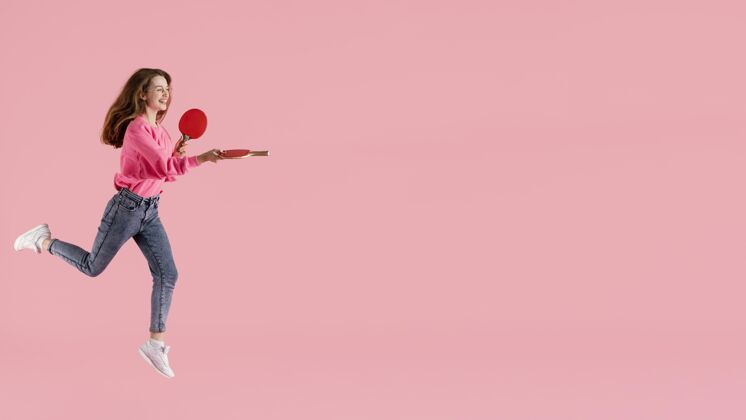 肖像肖像快乐的女子用乒乓球拍跳跃姿势年轻模特