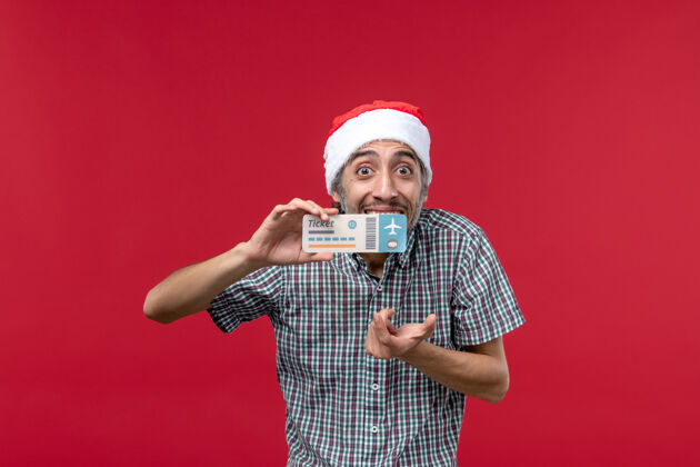 男人正面图：年轻男子手持红色背景的车票肖像脸圣诞节