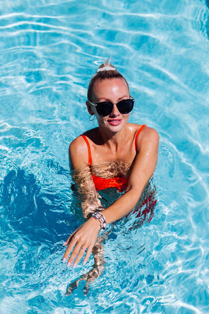 西装阳光明媚的日子里 蓝色游泳池里 戴着太阳镜 皮肤黝黑的平静快乐女人的画像优雅漂亮华丽