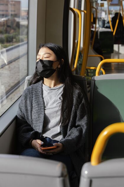年轻公共汽车上戴着面具的年轻女子面具姿势自然