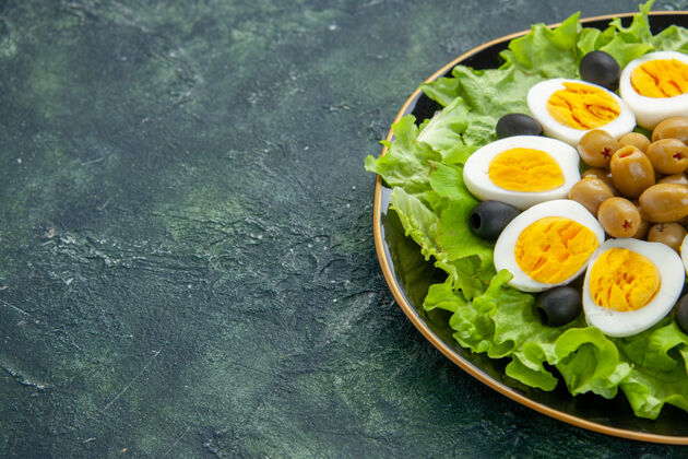 午餐前视图煮熟切片鸡蛋与橄榄和绿色沙拉在深蓝色的背景晚餐景观沙拉