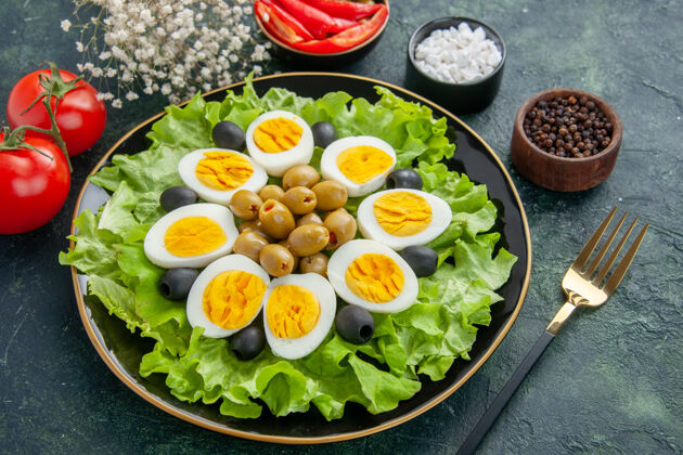 晚餐上图：深蓝色背景上的煮熟鸡蛋片 绿色沙拉和橄榄沙拉景观鸡蛋沙拉