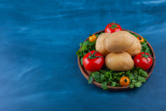 烹饪蓝色桌子上放着一盘新鲜土豆和西红柿生的蔬菜植物