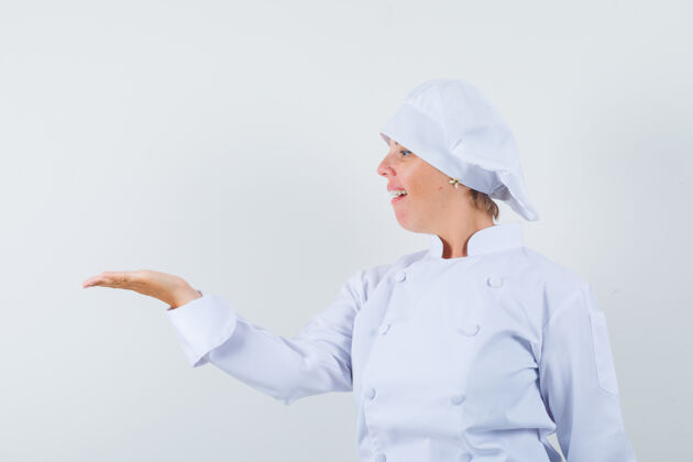自豪穿着白色制服的女厨师看着摊开的手掌 显得很自豪厨师蔓延时尚