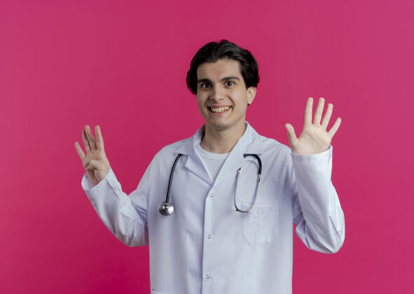 手面带微笑的年轻男医生穿着医用长袍和听诊器 显示九只手被隔离在粉红色的墙上医疗九年轻