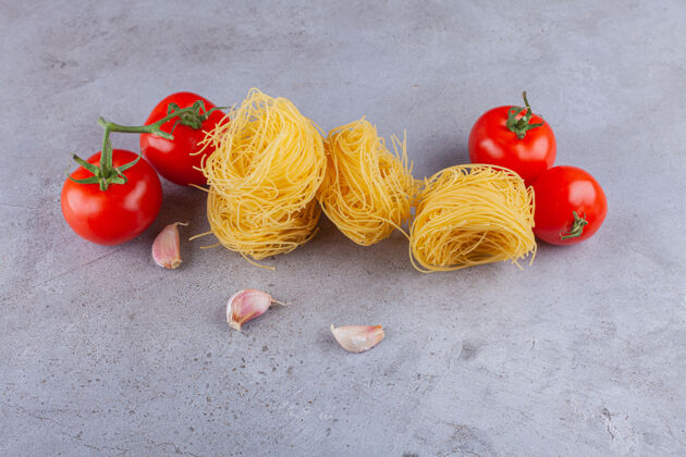 干意大利通心粉加新鲜的红色西红柿和蒜瓣做成的小窝晚餐菜肴球