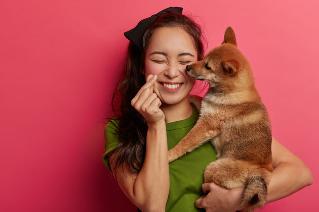 爱人 爱动物的概念积极的韩国女孩玩石坝犬 使迷你心手势女性拥抱主人
