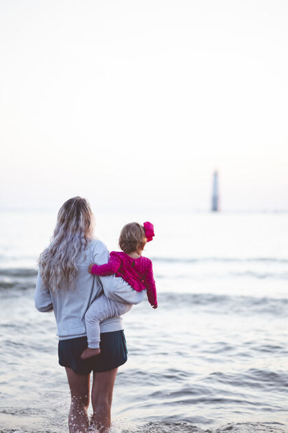 抱着一个母亲抱着她的孩子看海平面的垂直镜头人生活童年