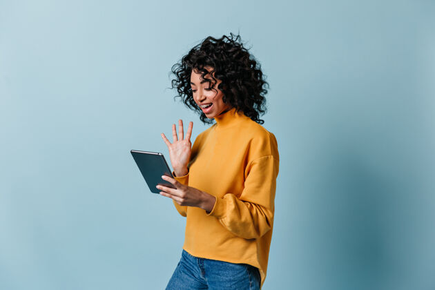 积极微笑的女人在数字平板电脑屏幕上挥手欢呼设备服装