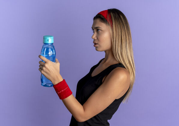 蓝色身穿黑色运动服 头戴红色头巾 手拿一瓶水 神情严肃的年轻健身女孩头带女孩水