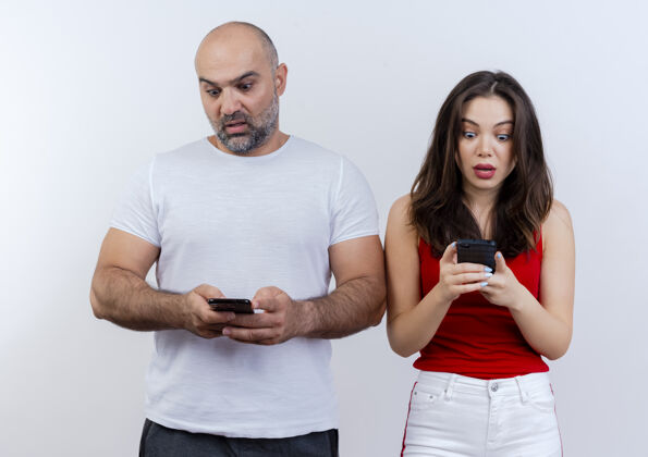 惊喜惊讶的成年夫妇都拿着手机看着他们的手机男人期待成人