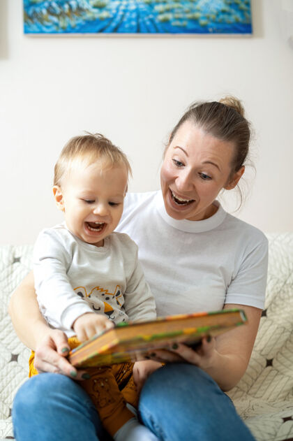 拥抱妈妈和她的孩子在家里的沙发上看书快乐而微笑享受父母大笑