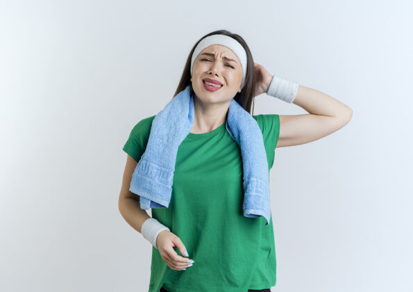 看戴着头带和手环 脖子上围着毛巾 手放在脑后 疼痛的年轻运动女性腕带运动头带