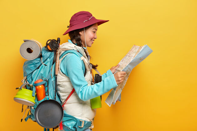 方向亚洲女游客学习地图 寻找新的目的地探索 独自旅行 戴帽子和活动服 携带大背包徒步旅行快乐旅行