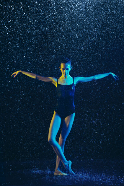 飞溅年轻的女芭蕾舞演员在水滴和浪花下表演白种人模特在霓虹灯下跳舞迷人的女人芭蕾舞和当代舞蹈概念水芭蕾舞喷雾