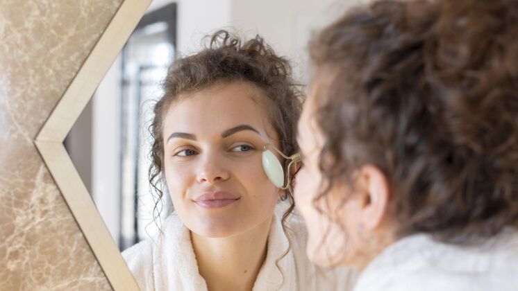 室内照镜子做面部按摩的女人女人自我护理镜子