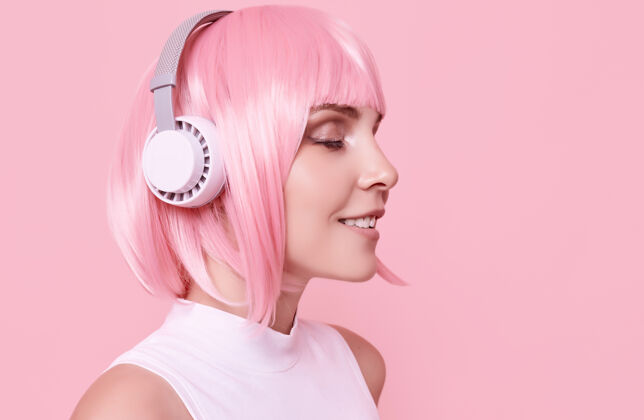 声音粉红头发的美女肖像在耳机里欣赏音乐快乐放松美丽