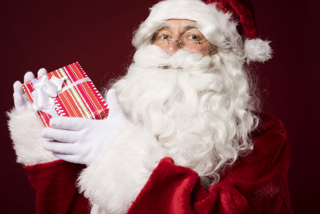 肖像圣诞老人带着一个红色背景的礼盒节日欢乐平安夜