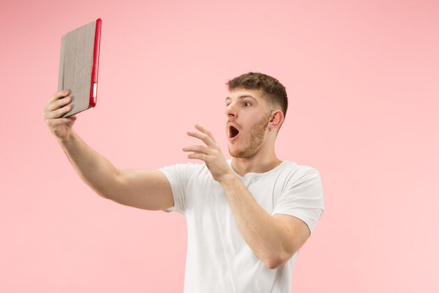 站立粉红色工作室里 一个微笑的男人指着笔记本电脑 空白屏幕被隔离笔记本电脑显示空白