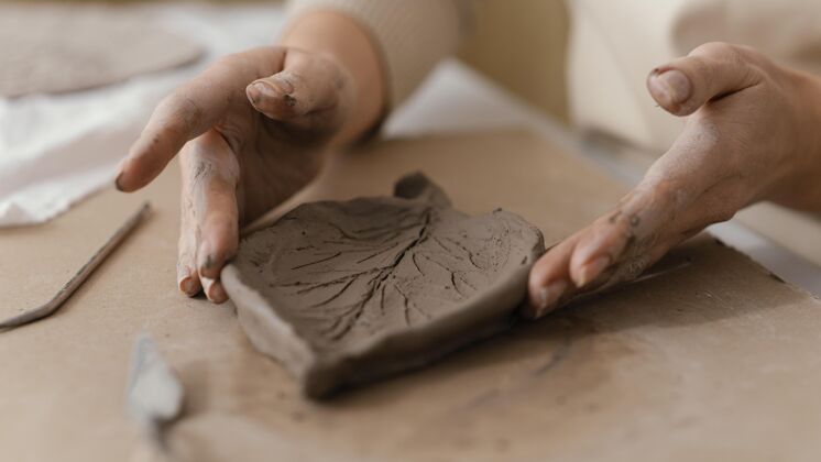 陶器双手紧握泥叶室内手工生活方式