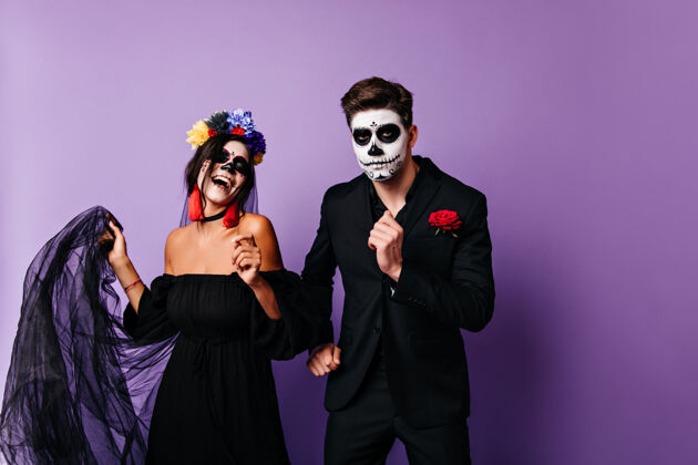 男人一个自信的墨西哥男人在死亡之日和女友跳舞一对穿着化装的夫妇在庆祝万圣节恐怖西班牙文化