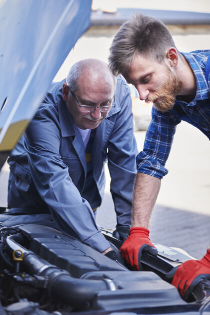 汽车修理厂修理工在车间里修理汽车发动机盖业务设备