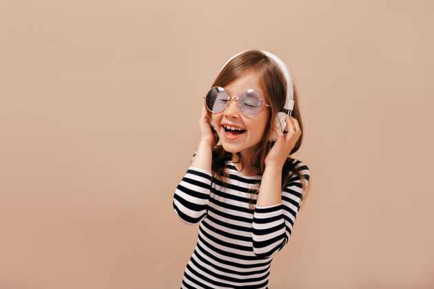 青春灵感小女孩在圆紫罗兰眼镜和脱衣衬衫有乐趣与闭上眼睛和灿烂的笑容媒体耳机太阳镜