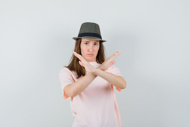 成人年轻的女性穿着粉色t恤 戴着帽子 表情严肃 展示着停下来的姿势 正面视图黑发微笑姿态