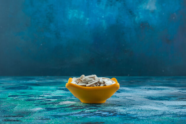 美味白色有机葵花籽放在蓝色的碗里葵花籽碗美味