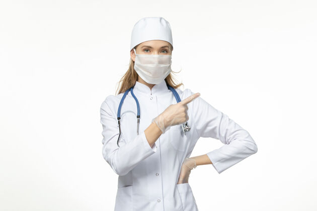药品正面图女医生穿着医疗服戴着口罩和手套因白色办公桌上的冠状病毒病冠状病毒-大流行性疾病医务人员视图疾病