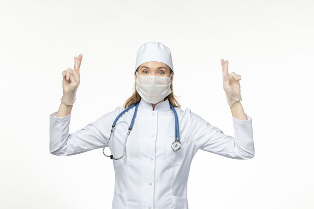 医生前视女医生身穿医疗服戴口罩因冠状病毒交叉手指轻拍白色病案-大流行病毒病疾病流行办公桌