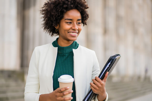 街道一幅非洲女商人的画像 她拿着一杯咖啡和一个剪贴板 在街上走在户外商业和城市概念户外咖啡成功