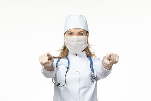 视野正面图女医生穿着医疗服 戴着口罩和手套 由于桌上的冠状病毒呈浅白色 大流行性冠状病毒大流行正面听诊器
