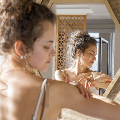 镜子女人照镜子 在手上涂面霜女人室内美容