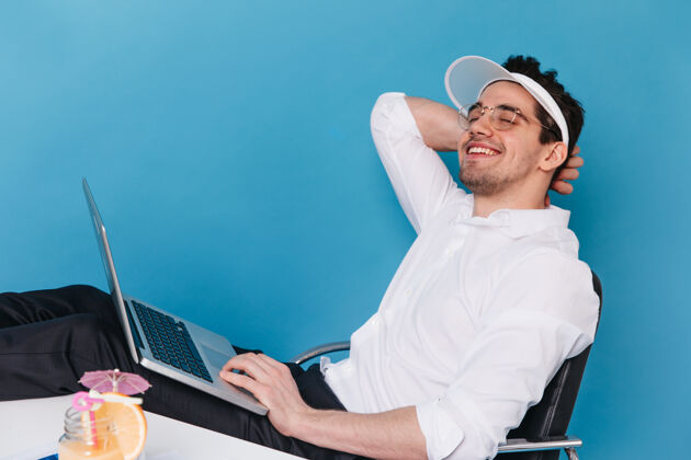 经典戴着眼镜 戴着白帽子 穿着衬衫 微笑着拿着笔记本电脑的快乐男人的画像官方现代老板
