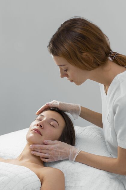 美容护理美容师与女性客户在沙龙进行面部护理美容治疗面部护理美容治疗