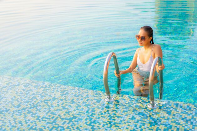 蓝色肖像美丽的亚洲年轻女子放松微笑在度假酒店游泳池周围享受休闲度假健康休闲旅游